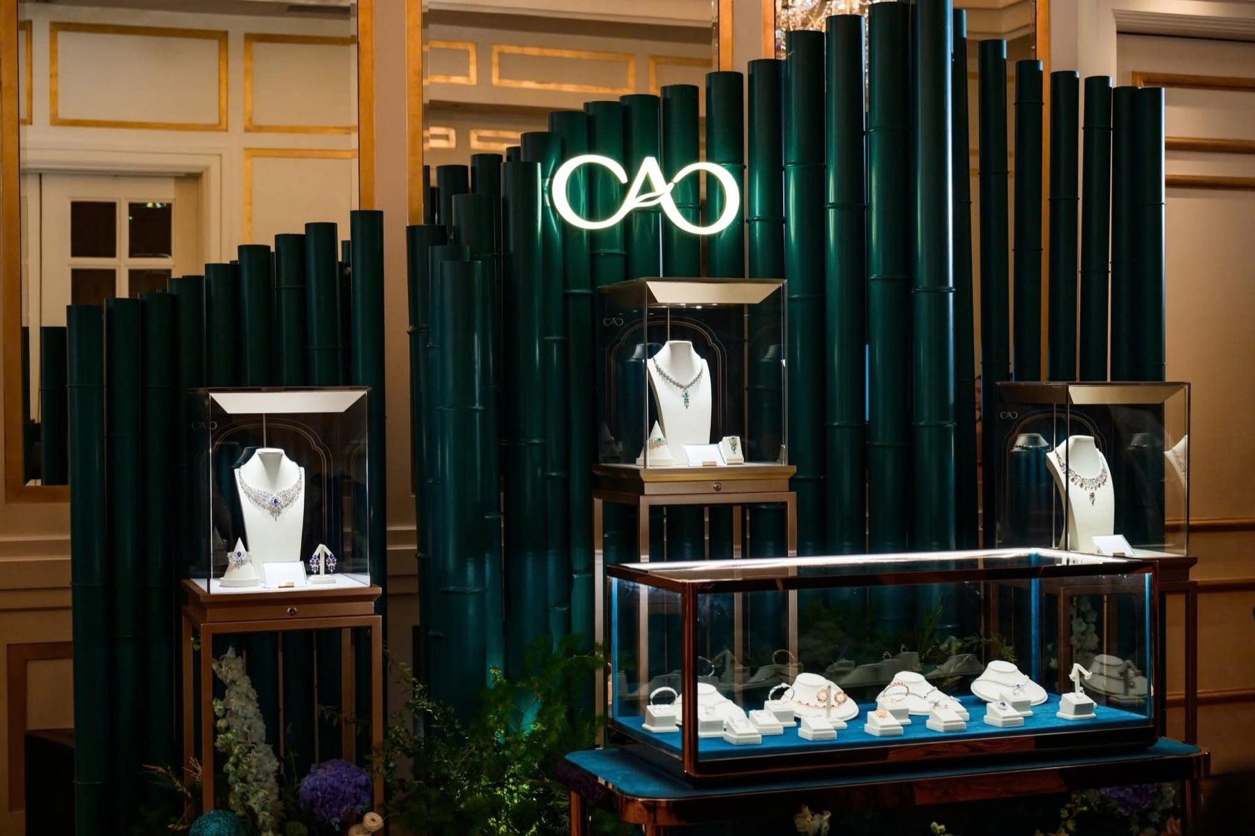 Illuminated CAO logo above a green bamboo high-jewelry display