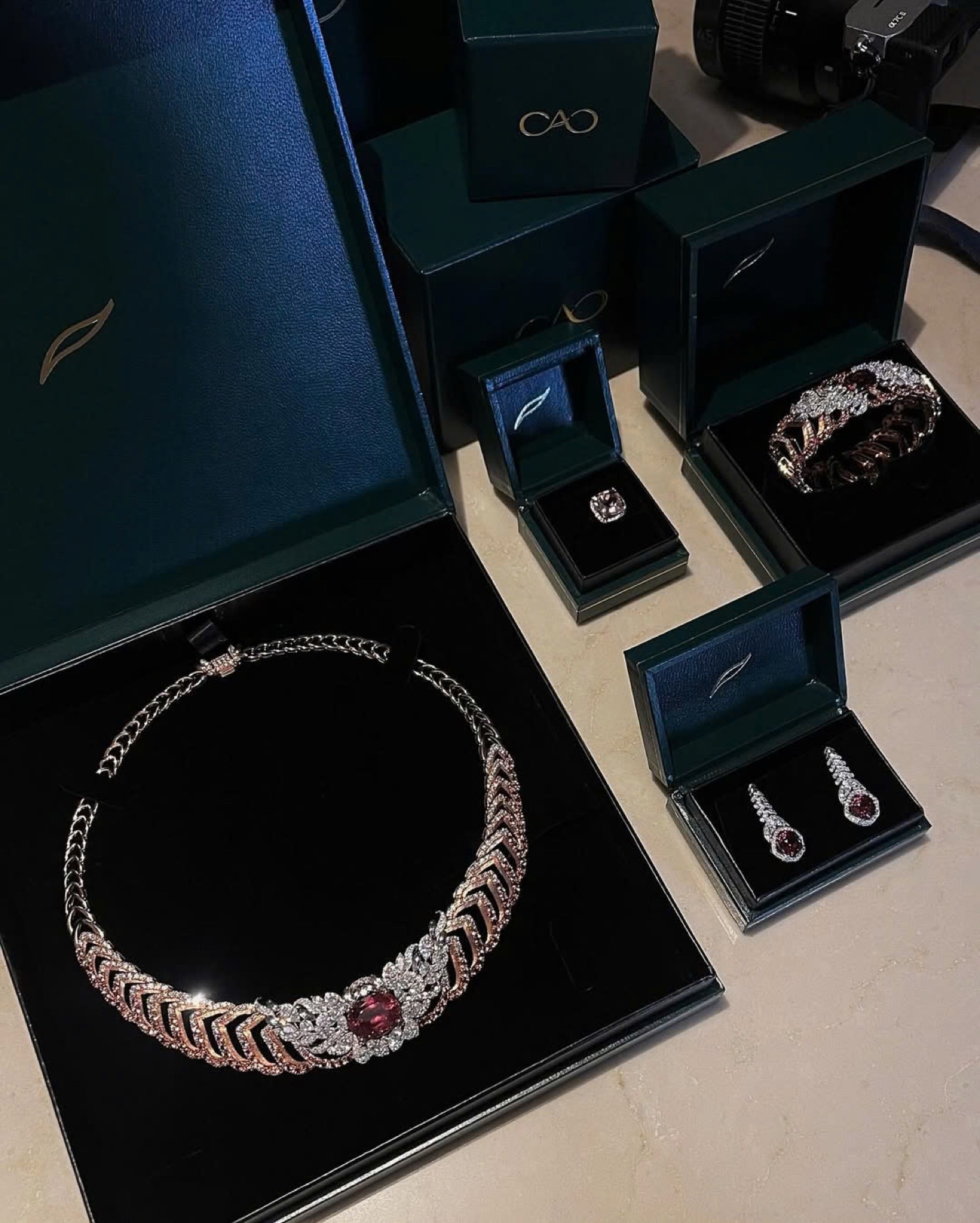 A CAO ruby high-jewelry suite in its presentation boxes on set